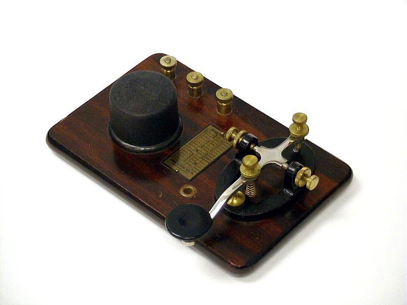 <b>Signal KOB</b> (1945) : Figure 57 : Telegraph Key and Buzzer on base. Brass hardware, steel lever key with black cast iron base mounted on a wooden base with a round black buzzer. Morse Code brass plate. Wiring diagram on the bottom. : 